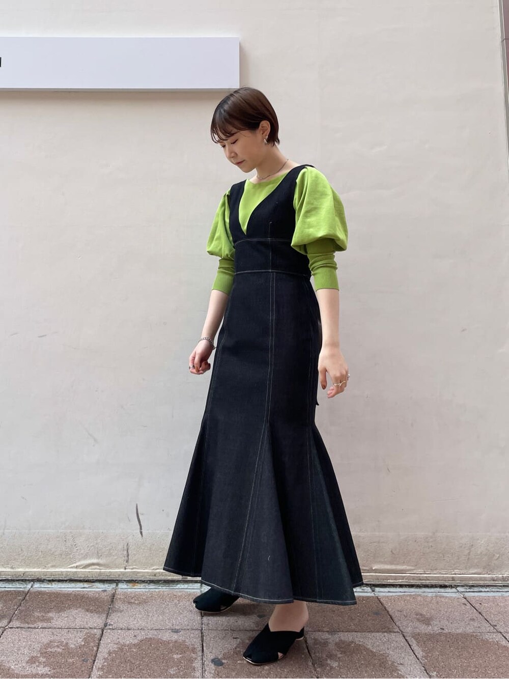 ブラック系のワンピース、グリーン系のニット/セーター、ブラック系のサンダルを着用したレディースの春コーディネートの2枚目の写真