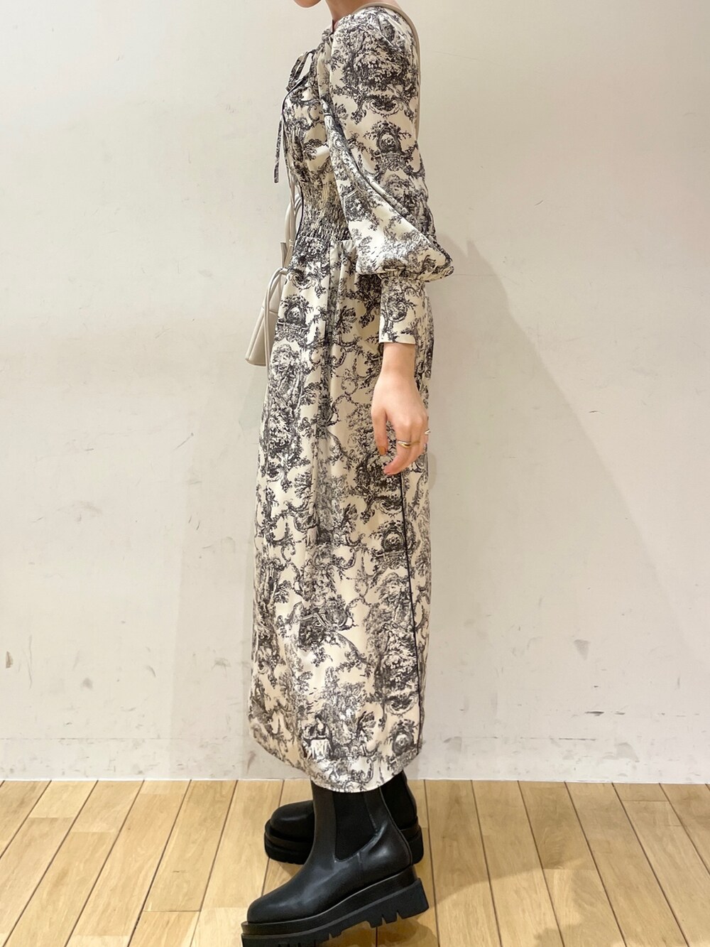 ホワイト系のワンピース、ブラック系のブーツ、ホワイト系のハンドバッグを着用したレディースの冬コーディネートの3枚目の写真