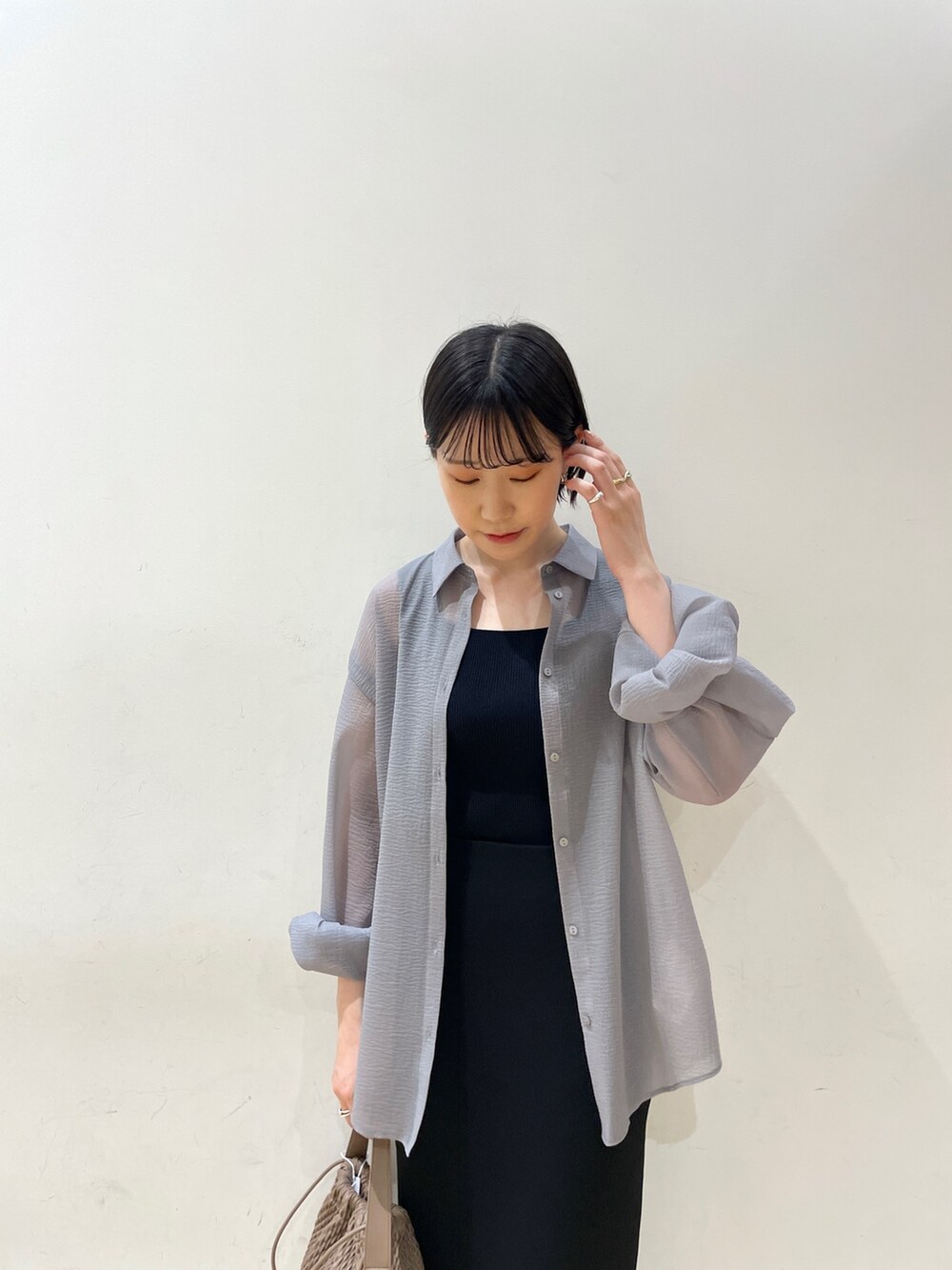 ブラック系のスカート、ブラウン系のハンドバッグ、ブラック系のサンダルを着用したレディースの春コーディネートの5枚目の写真