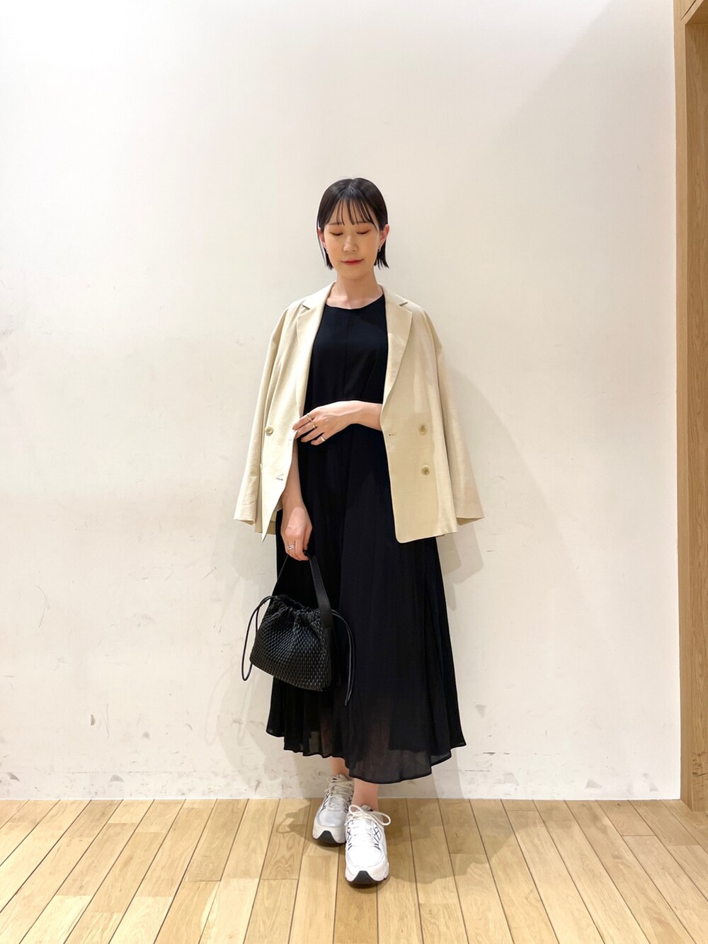 ブラック系のハンドバッグ、ベージュ系のテーラードジャケット、ブラック系のワンピースを着用したレディースの夏コーディネートの7枚目の写真
