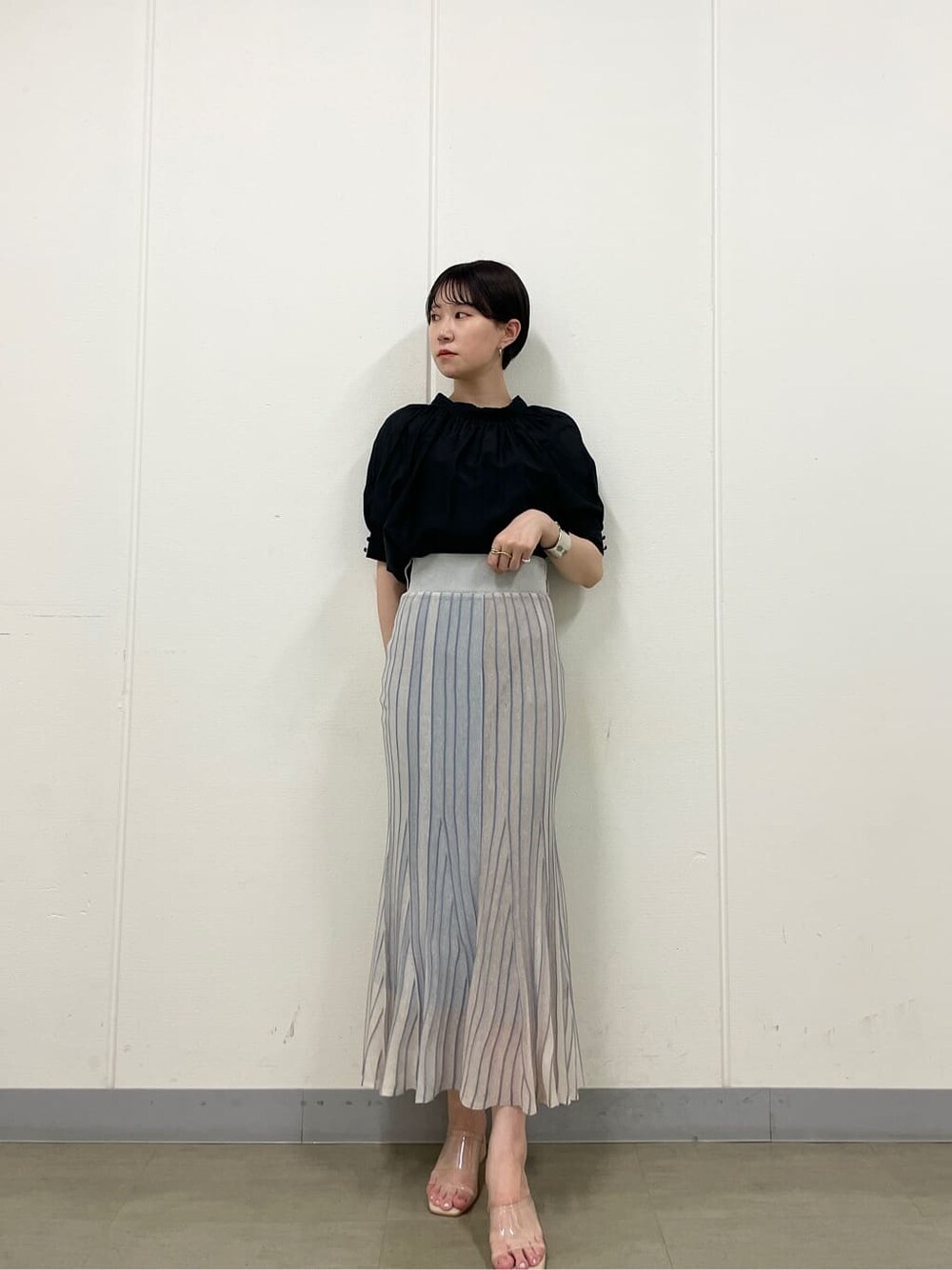 ブルー系のスカート、ホワイト系のサンダル、ブラック系のシャツ/ブラウスを着用したレディースの夏コーディネートの4枚目の写真