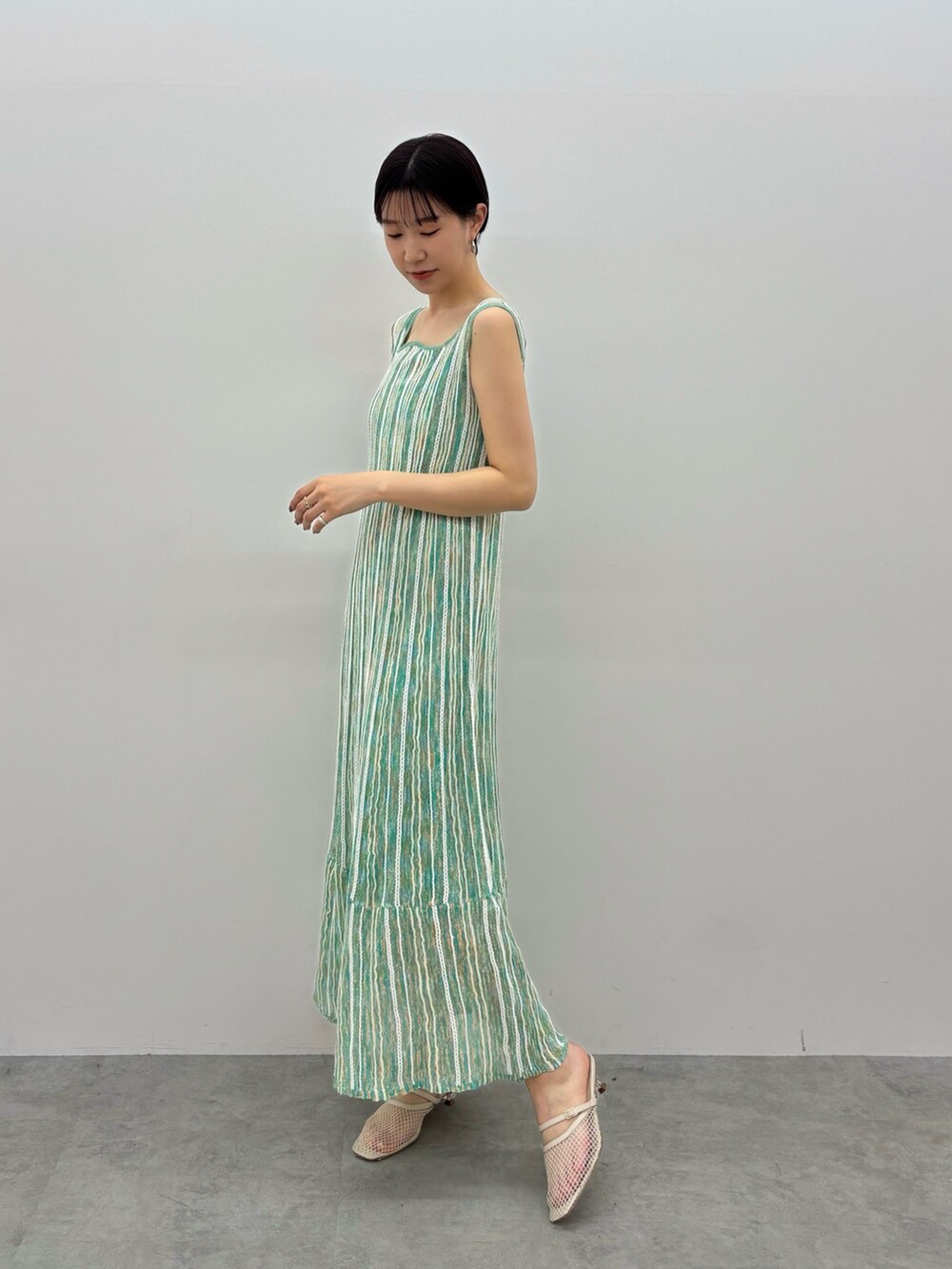 グリーン系のワンピース、ホワイト系のサンダル、シルバー系のピアス（両耳用）を着用したレディースの春コーディネートの2枚目の写真