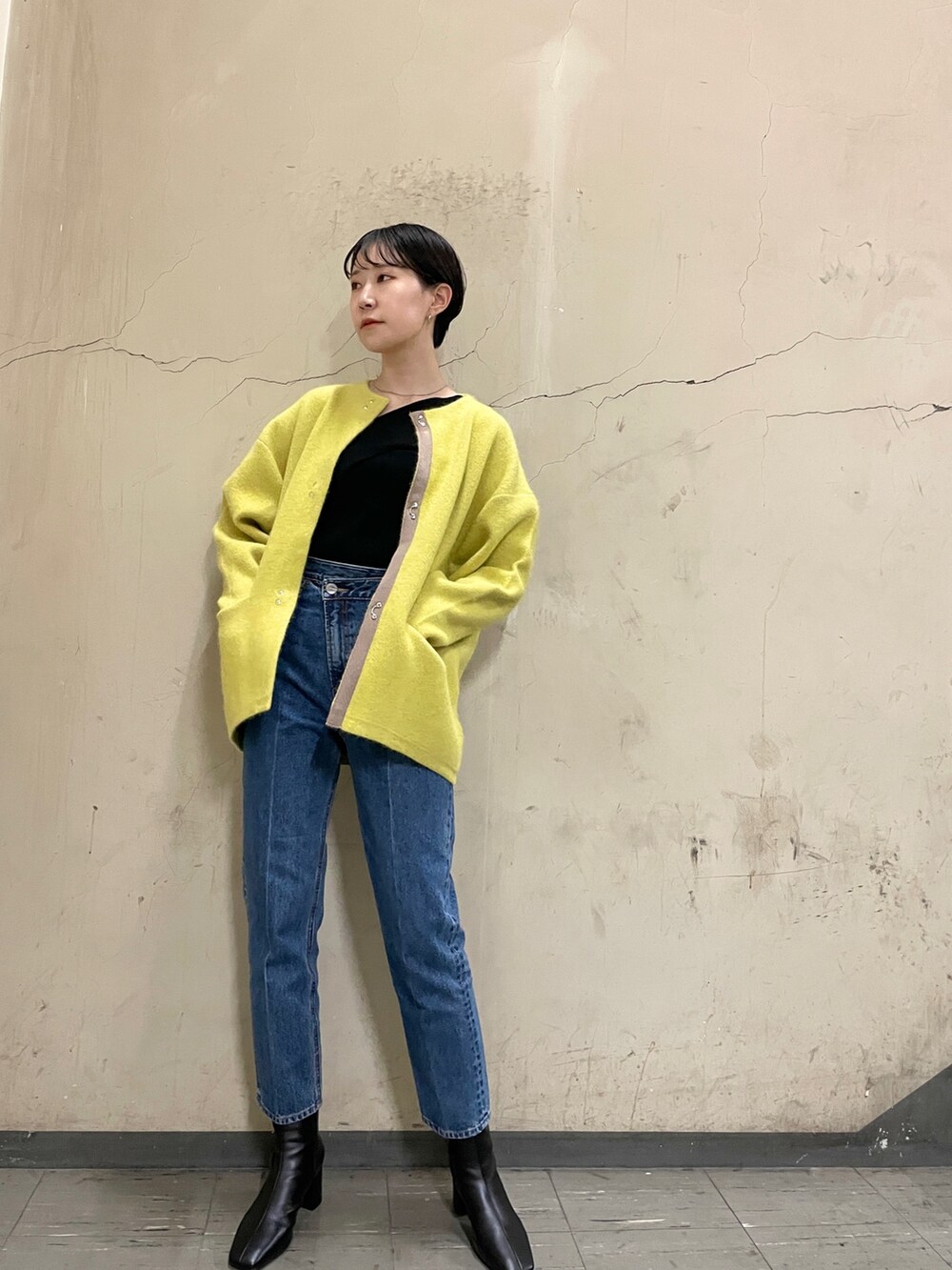 ブラック系のニット/セーター、イエロー系のカーディガン/ボレロ、ブルー系のデニムパンツを着用したレディースの秋コーディネートの2枚目の写真