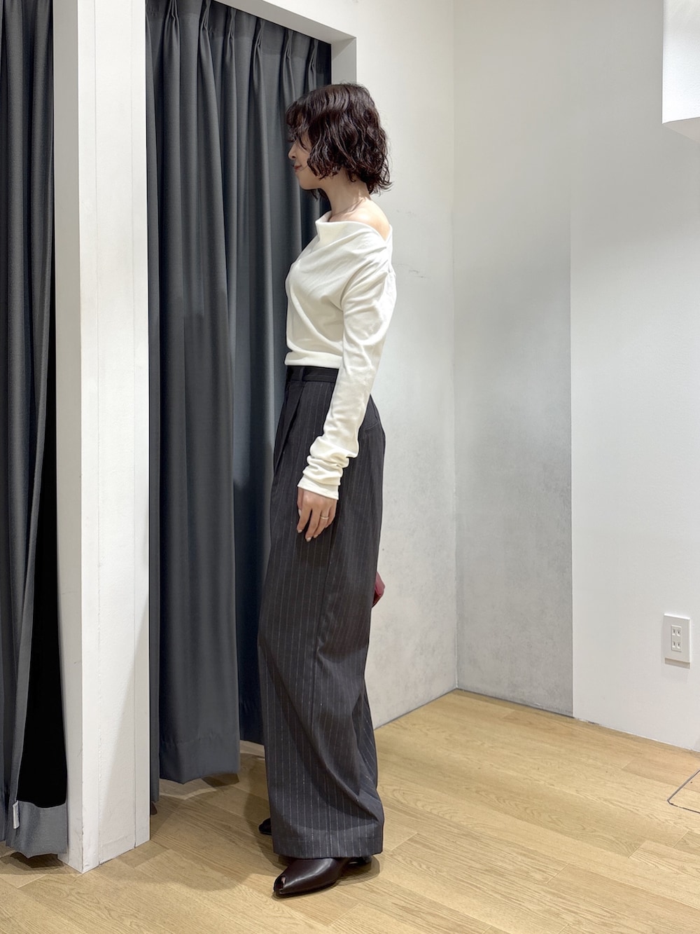 グレー系のその他パンツ、ホワイト系のニット/セーター、レッド系のハンドバッグを着用したレディースの秋コーディネートの2枚目の写真