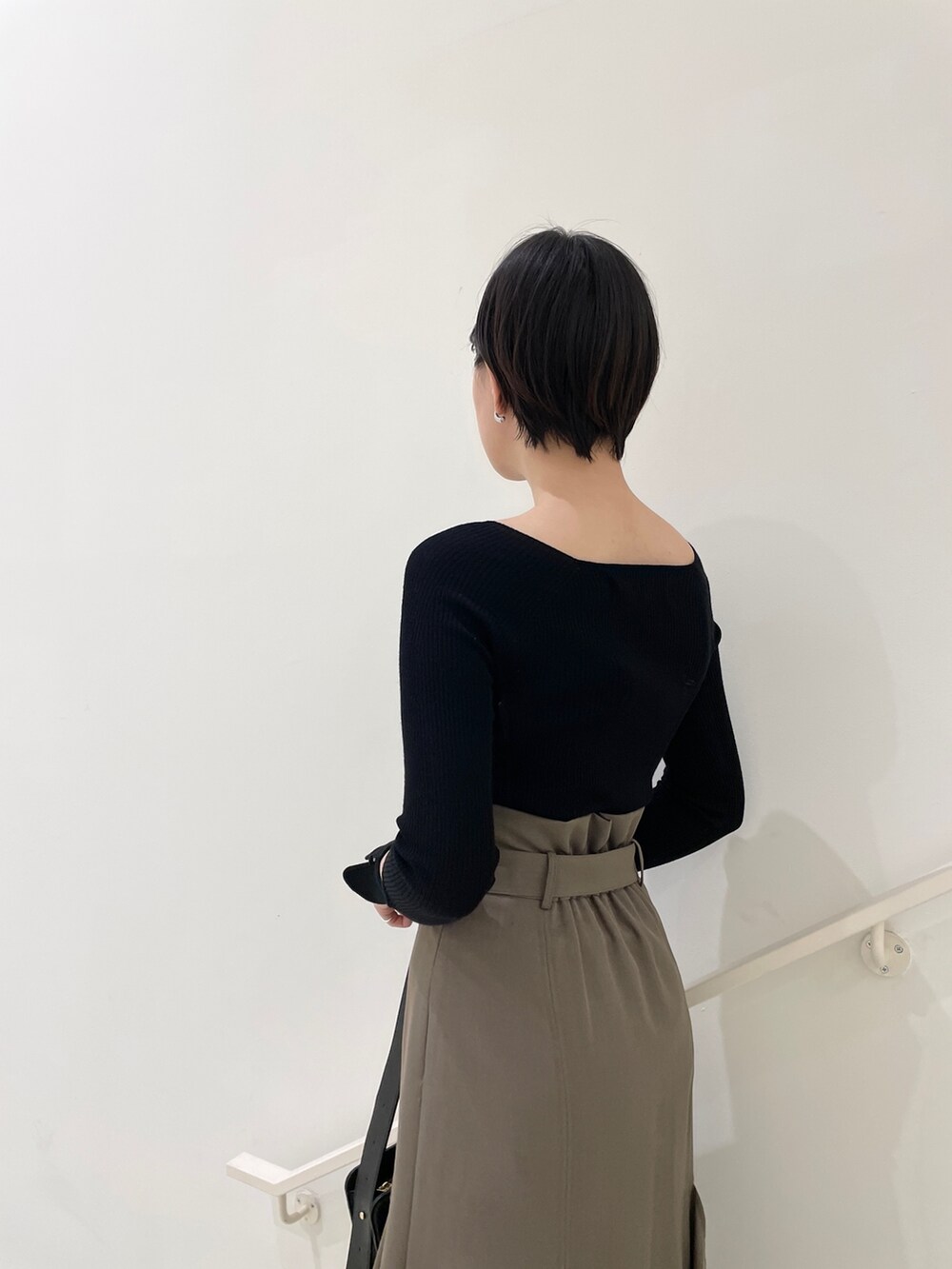 ブラウン系のスカート、ブラック系のニット/セーター、ベージュ系のサンダルを着用したレディースの春コーディネートの8枚目の写真