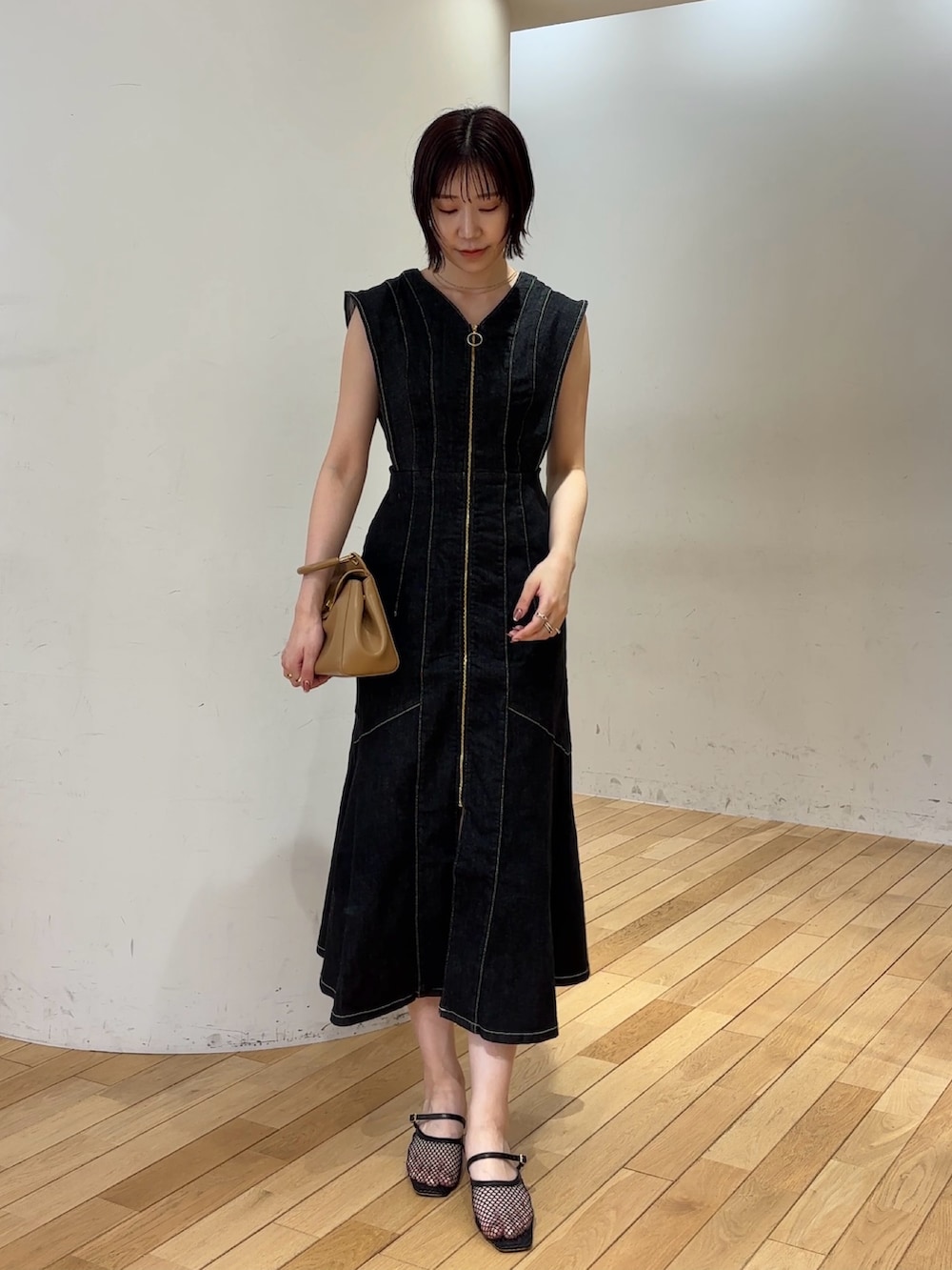 ブラック系のワンピース、ブラック系のサンダル、イエロー系のハンドバッグを着用したレディースの夏コーディネートの2枚目の写真