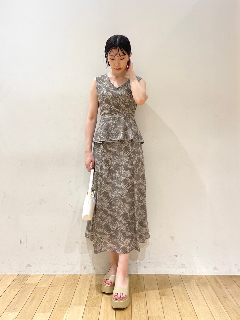 グレー系のワンピース、ホワイト系のハンドバッグ、ベージュ系のサンダルを着用したレディースの夏コーディネートの4枚目の写真