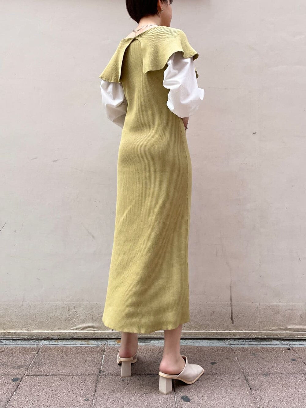 ベージュ系のハンドバッグ、ベージュ系のトレンチコート、イエロー系のワンピースを着用したレディースの冬コーディネートの3枚目の写真