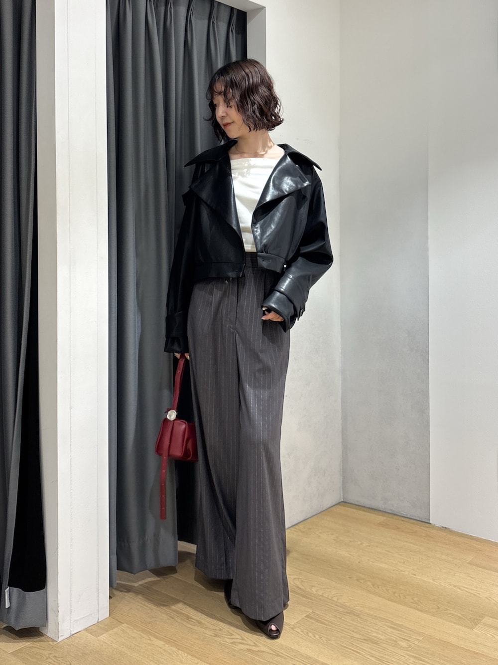 グレー系のその他パンツ、ホワイト系のニット/セーター、レッド系のハンドバッグを着用したレディースの秋コーディネートの2枚目の写真