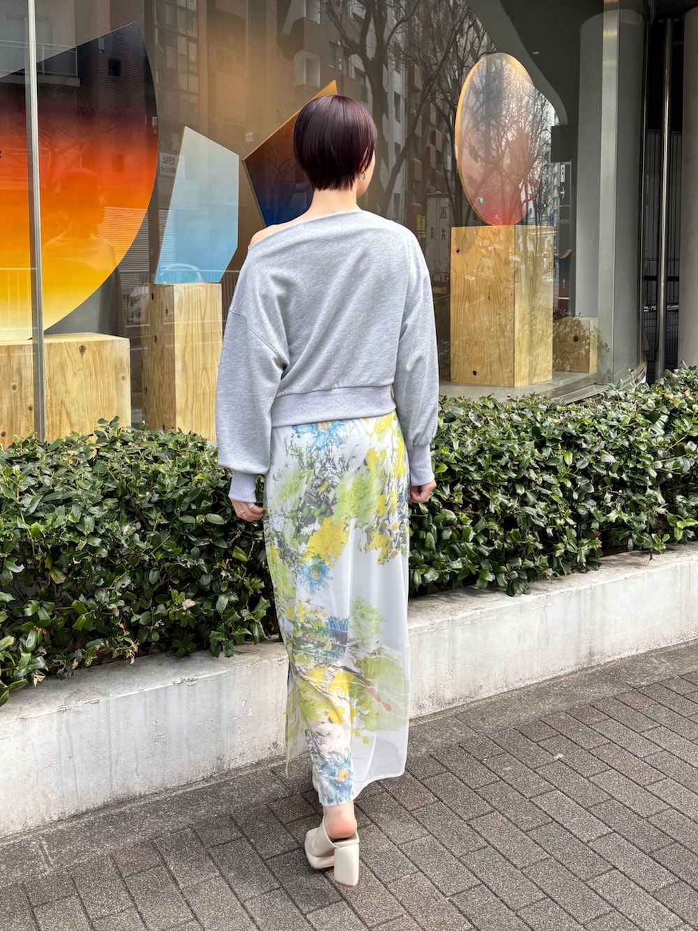 グレー系のスカート、グレー系のスウェット、ホワイト系のサンダルを着用したレディースの冬コーディネートの2枚目の写真