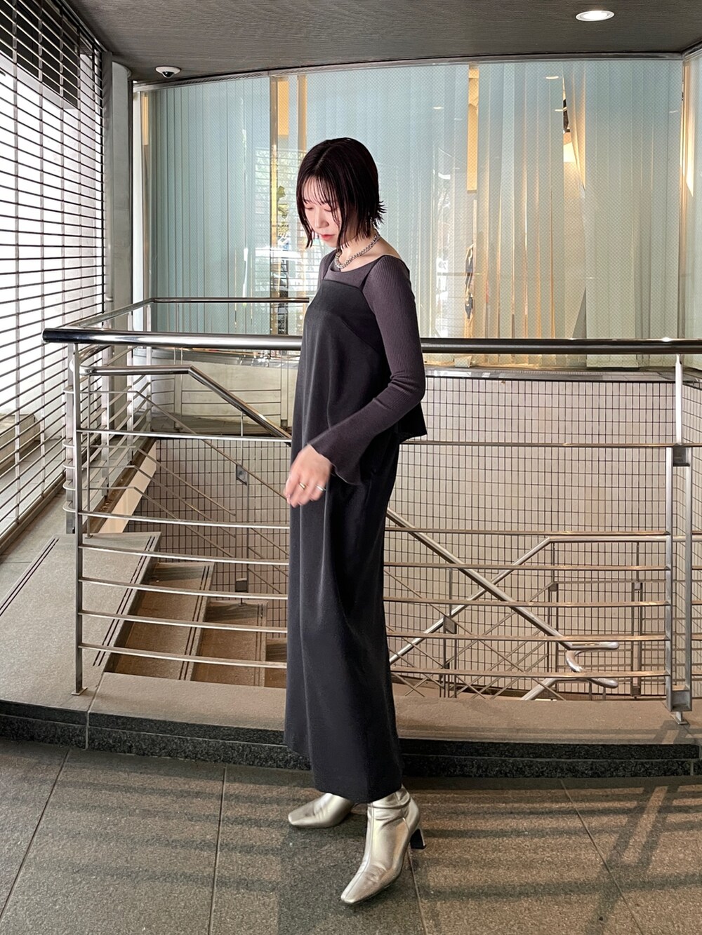 グレー系のニット/セーター、シルバー系のブーツ、ブラック系のワンピースを着用したレディースの秋コーディネートの2枚目の写真