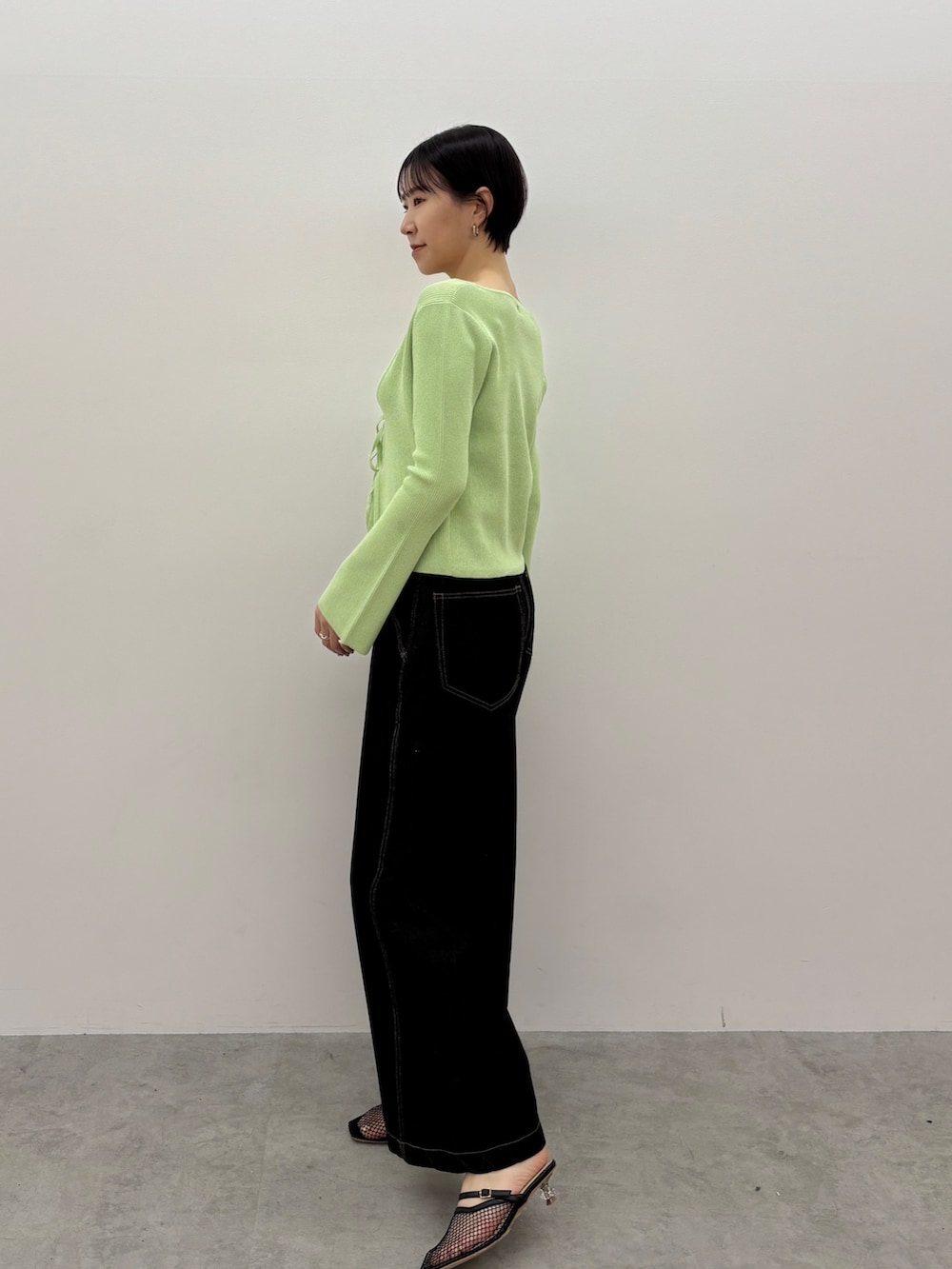 グリーン系のアンサンブル、ブラック系のデニムパンツ、ブラック系のサンダルを着用したレディースの春コーディネートの3枚目の写真