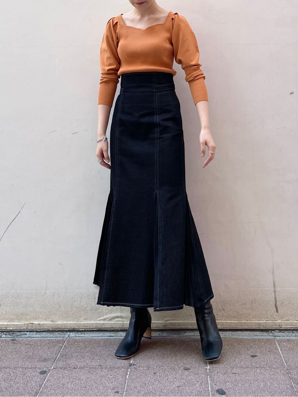 ブラック系のその他シューズ、オレンジ系のニット/セーター、ブラック系のスカートを着用したレディースの冬コーディネートの4枚目の写真