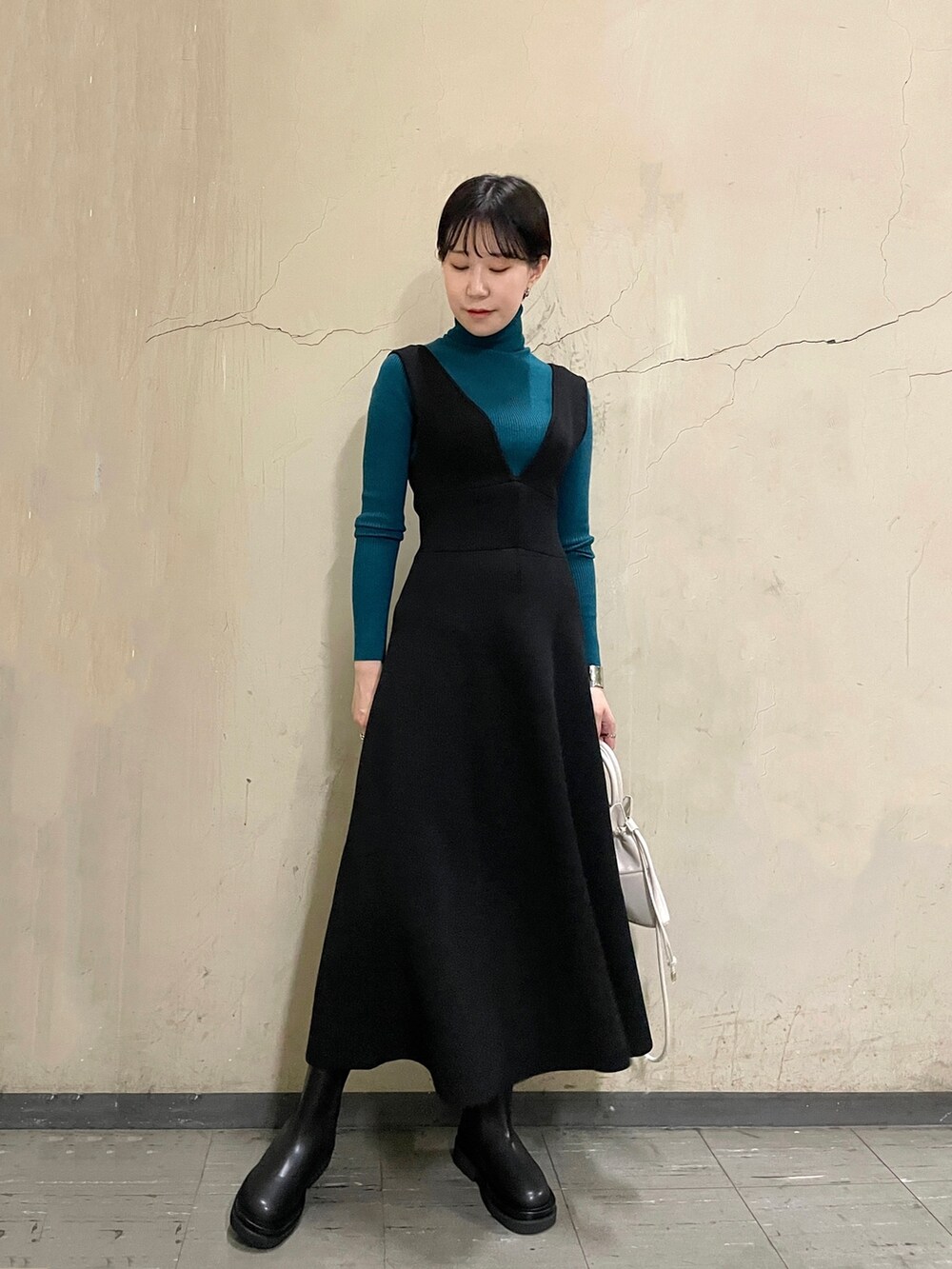 ブラック系のスカート、グリーン系のニット/セーター、ブラック系のブーツを着用したレディースの秋コーディネートの2枚目の写真