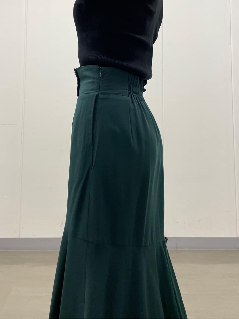 グリーン系のスカート、ブラック系のブーツ、ブラック系のニット/セーターを着用したレディースの秋コーディネートの7枚目の写真