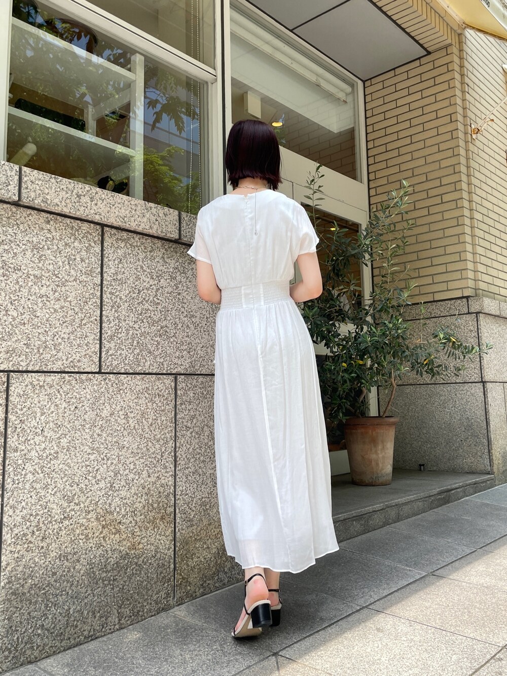 ブラウン系のショルダーバッグ、ホワイト系のワンピース、シルバー系のチョーカーを着用したレディースの夏コーディネートの4枚目の写真