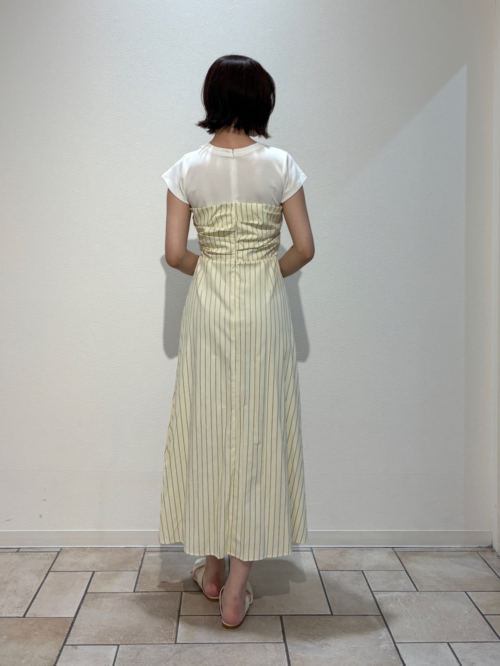 イエロー系のワンピース、ホワイト系のサンダル、ブラウン系のハンドバッグを着用したレディースの夏コーディネートの3枚目の写真