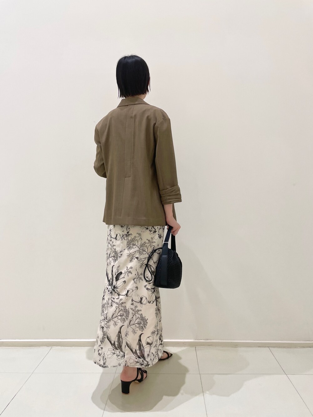 ブラウン系のテーラードジャケット、ベージュ系のニット/セーター、ホワイト系のスカートを着用したレディースの春コーディネートの4枚目の写真