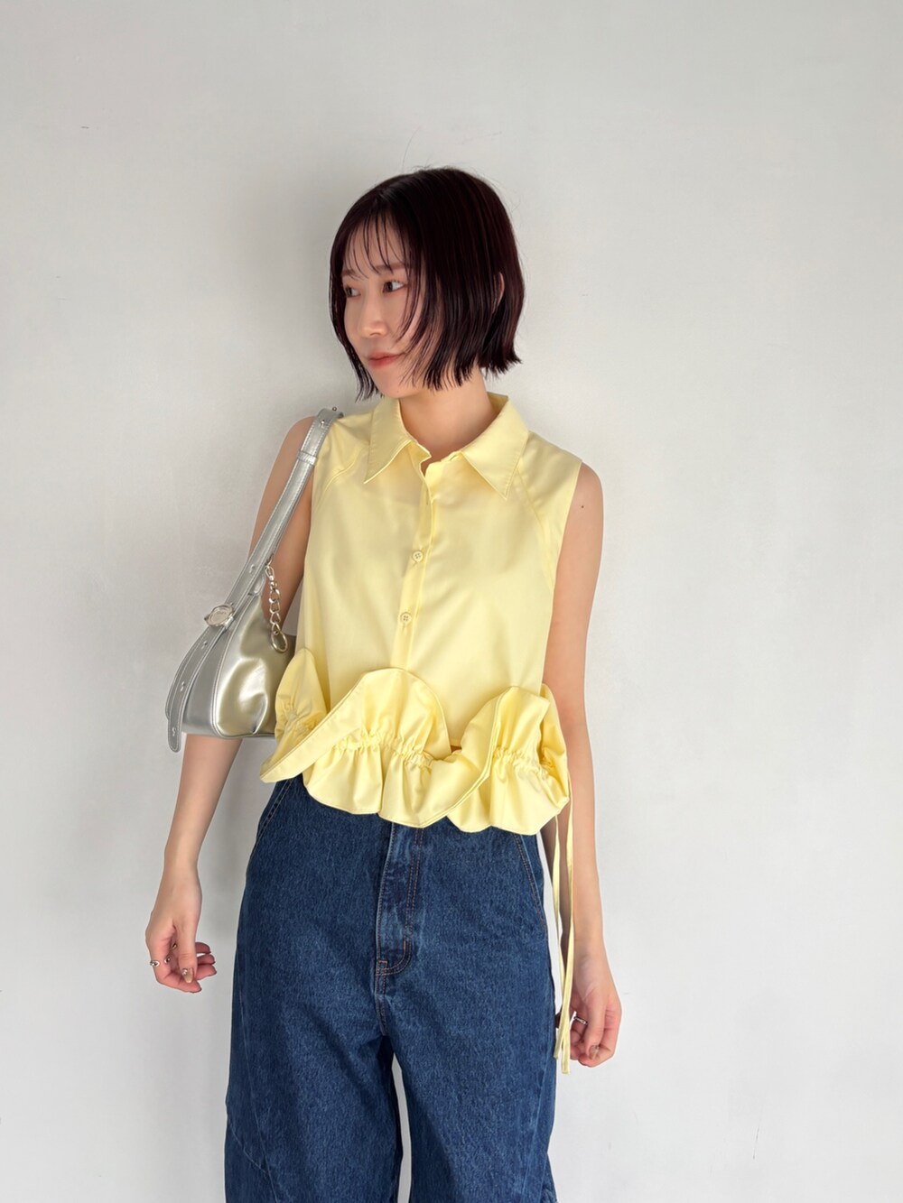 ブルー系のデニムパンツ、イエロー系のシャツ/ブラウス、シルバー系のハンドバッグを着用したレディースの夏コーディネートの4枚目の写真