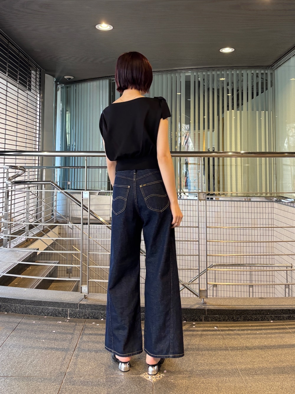 ブルー系のデニムパンツ、ブラック系のパンプス、ブラック系のニット/セーターを着用したレディースの春コーディネートの2枚目の写真