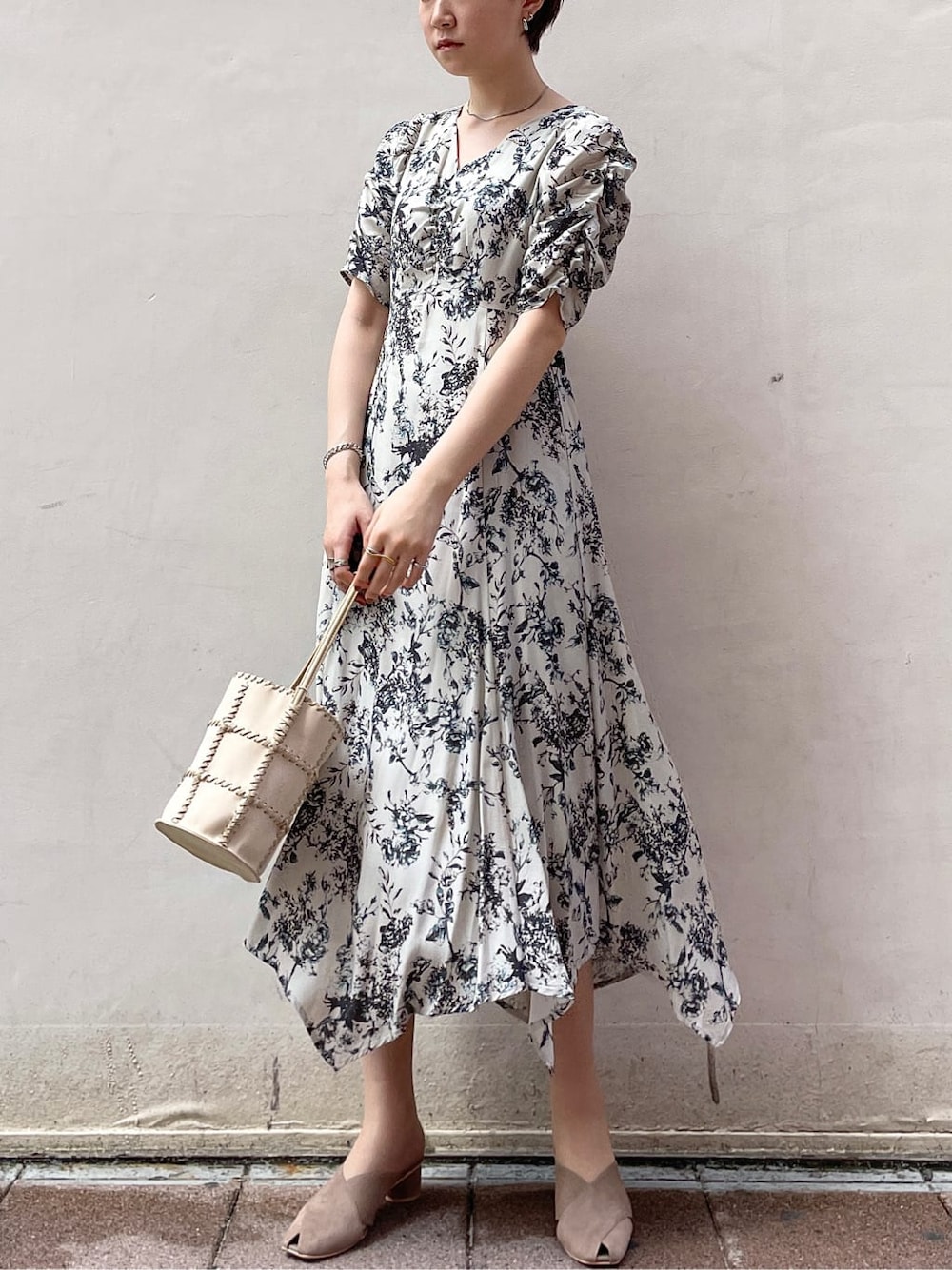 グレー系のワンピース、ブラック系のサンダル、ホワイト系のショルダーバッグを着用したレディースの春コーディネートの2枚目の写真