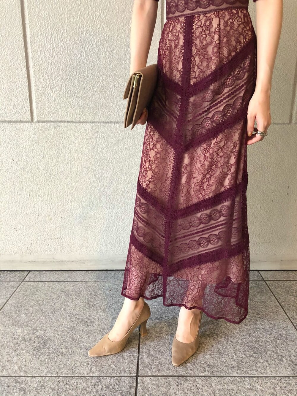 レッド系のドレス、ベージュ系のパンプス、ベージュ系のクラッチバッグを着用したレディースの秋コーディネートの7枚目の写真