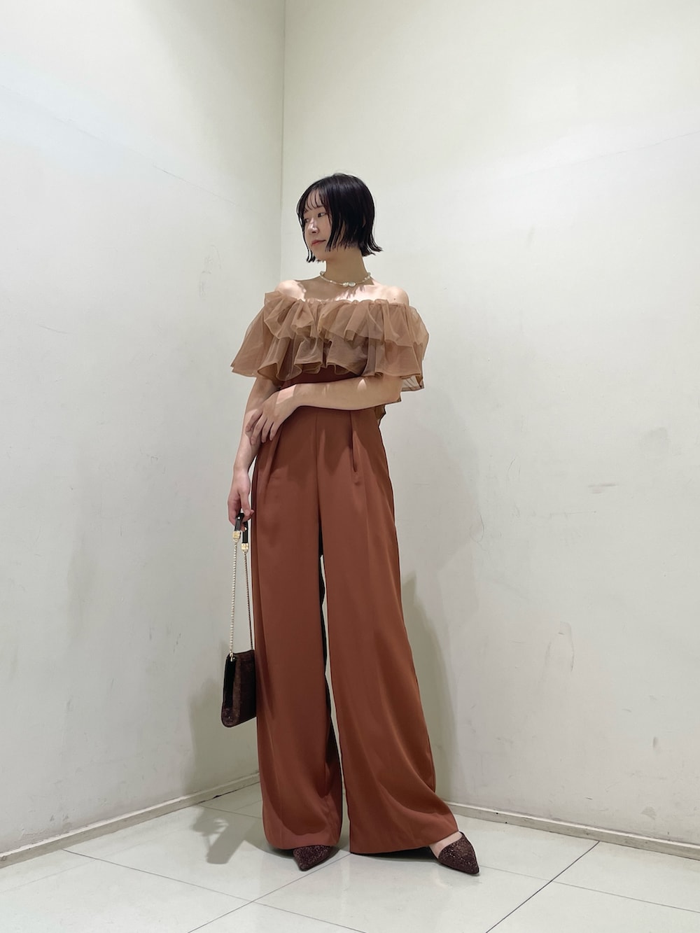 オレンジ系のパンツドレス、その他のクラッチバッグ、その他のパンプスを着用したレディースの夏コーディネートの2枚目の写真