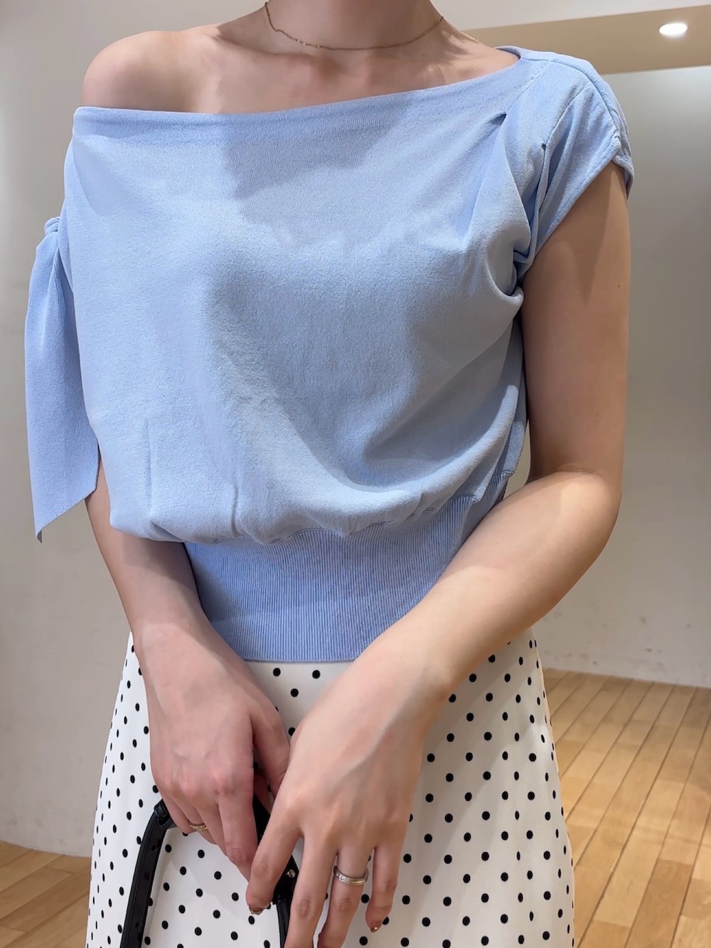 ブルー系のニット/セーター、ホワイト系のスカート、ブラック系のハンドバッグを着用したレディースの夏コーディネートの4枚目の写真