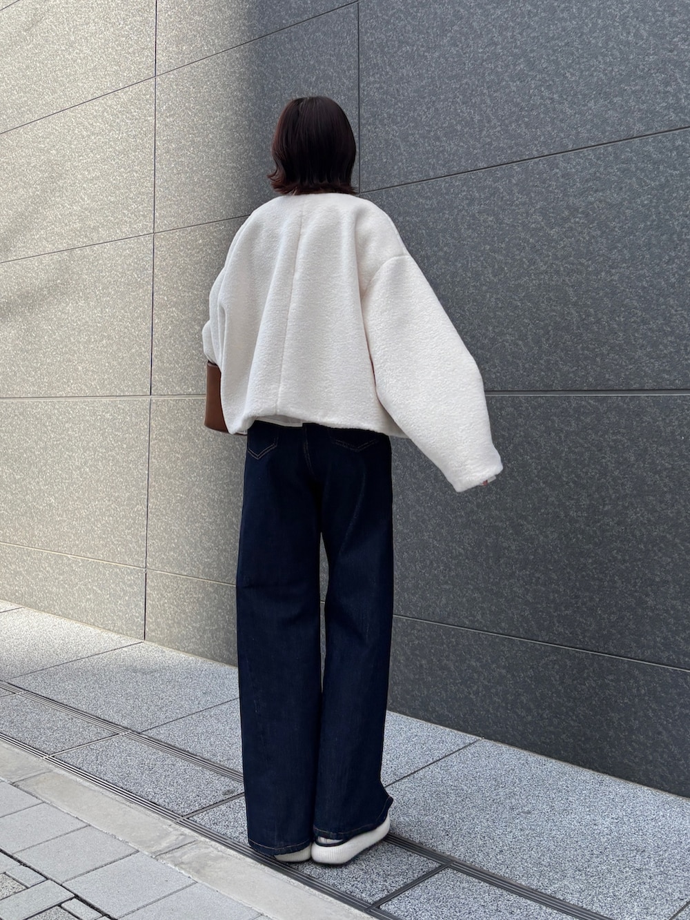 ホワイト系のブルゾン、ブルー系のデニムパンツ、イエロー系のハンドバッグを着用したレディースの冬コーディネートの3枚目の写真