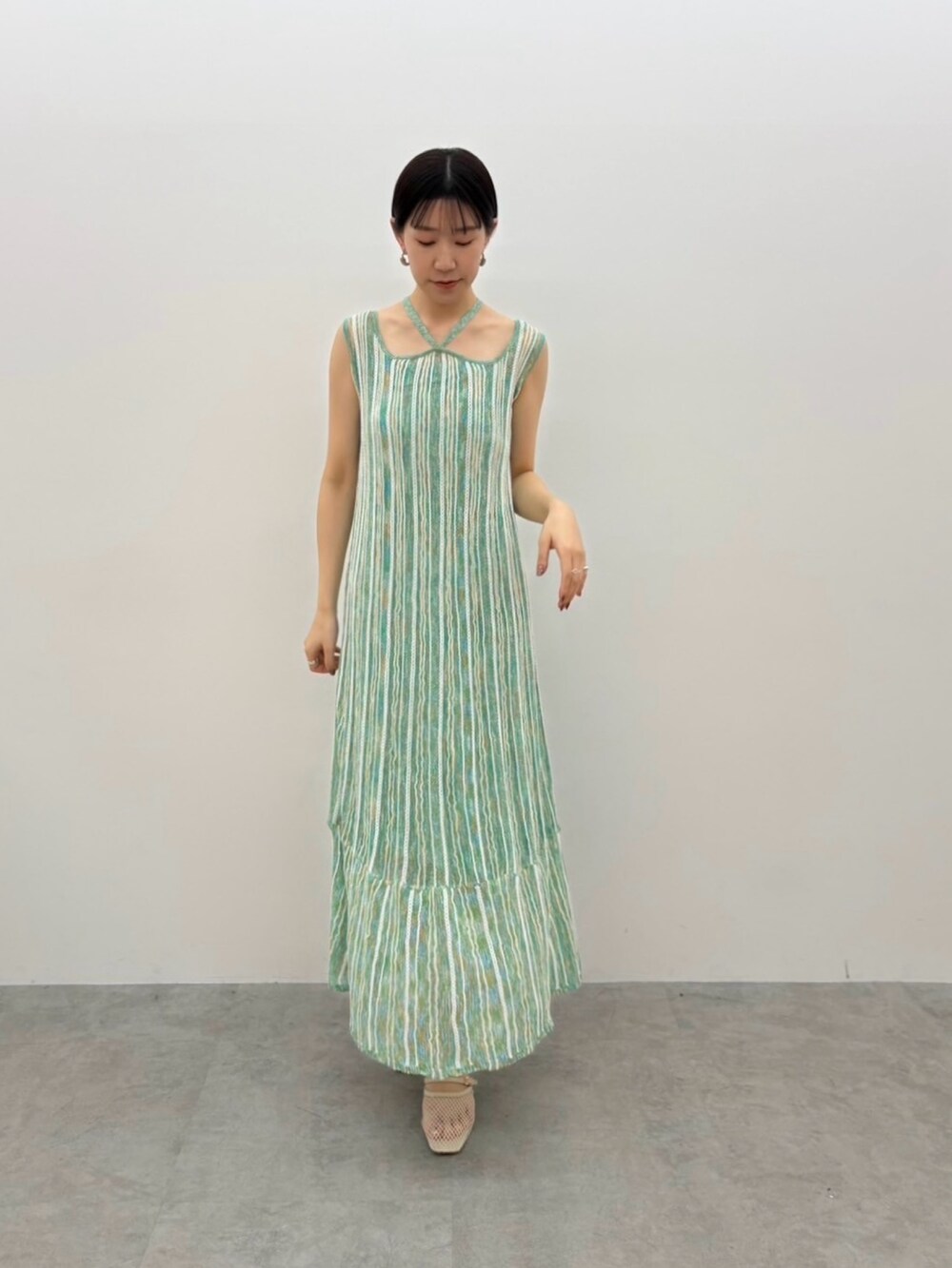 グリーン系のワンピース、ホワイト系のサンダル、シルバー系のピアス（両耳用）を着用したレディースの春コーディネートの6枚目の写真