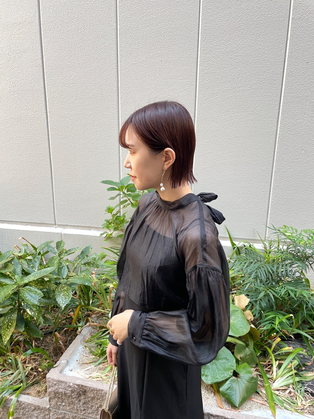 ブラック系のドレス、その他のパンプス、ゴールド系のハンドバッグを着用したレディースの秋コーディネートの6枚目の写真