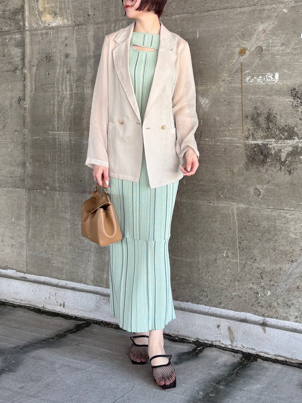 グリーン系のワンピース、ホワイト系のテーラードジャケット、ブラック系のサンダルを着用したレディースの春コーディネートの3枚目の写真