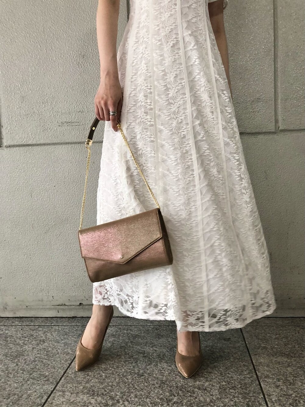 ホワイト系のドレス、ゴールド系のパンプス、ゴールド系のクラッチバッグを着用したレディースの夏コーディネートの5枚目の写真