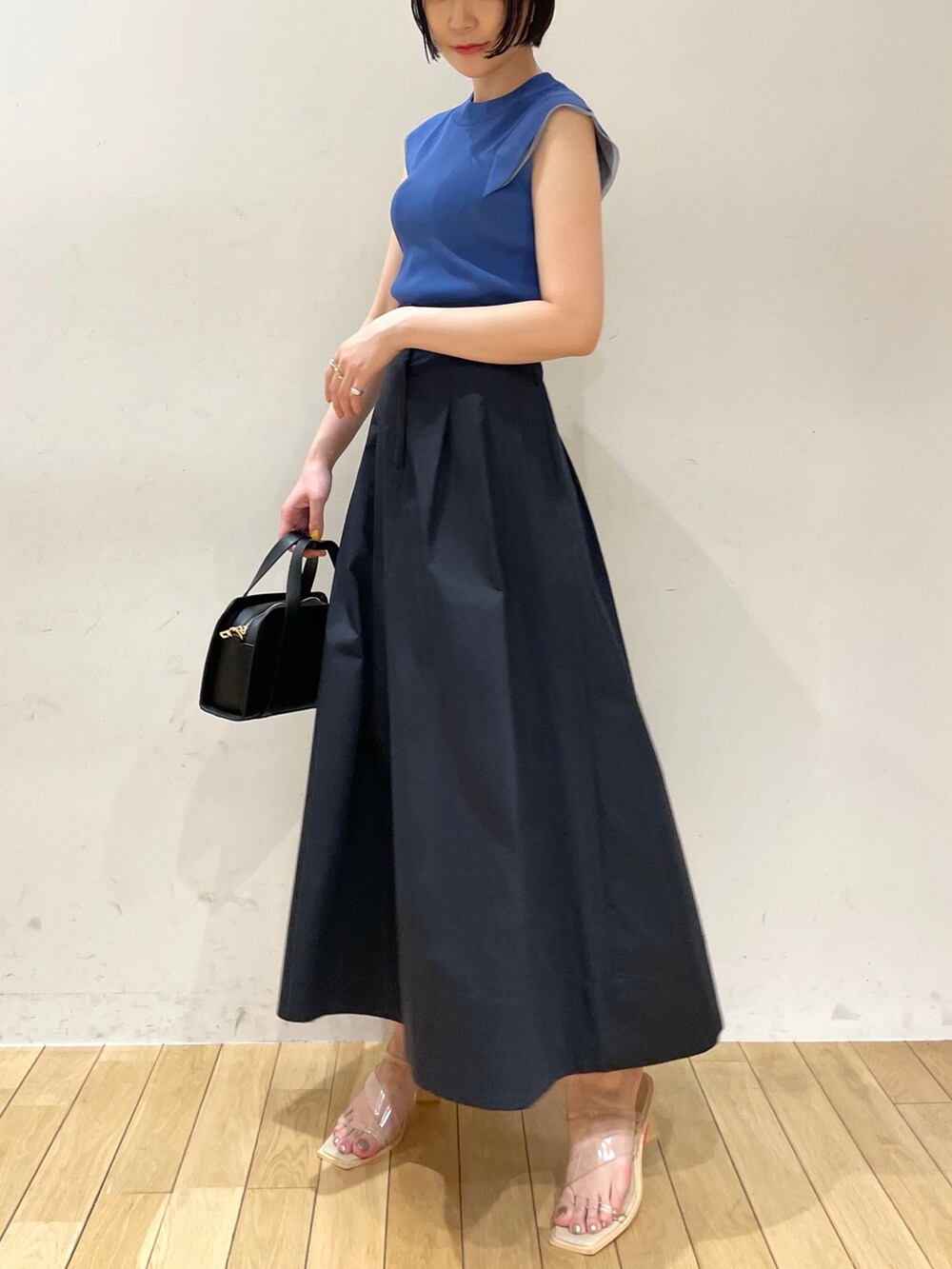 ブルー系のスカート、ブルー系のニット/セーター、ブラック系のショルダーバッグを着用したレディースの夏コーディネートの5枚目の写真