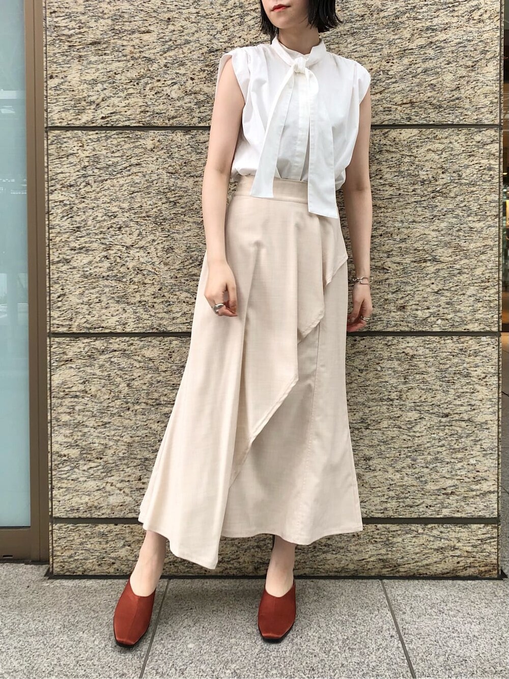 ホワイト系のシャツ/ブラウス、ホワイト系のスカート、オレンジ系のスリッポンを着用したレディースの夏コーディネートの2枚目の写真