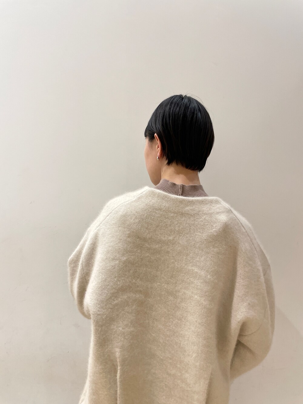 ホワイト系のカーディガン/ボレロ、ベージュ系のワンピース、ホワイト系のハンドバッグを着用したレディースの冬コーディネートの7枚目の写真