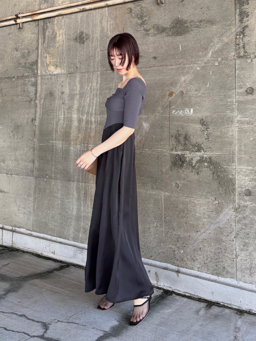ブラック系のワンピース、ブラック系のサンダル、イエロー系のハンドバッグを着用したレディースの夏コーディネートの3枚目の写真