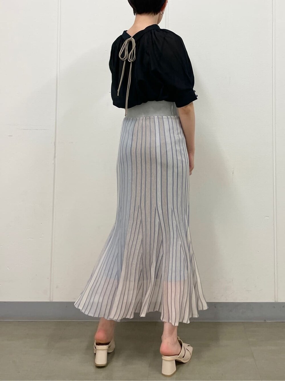 ブルー系のスカート、ホワイト系のサンダル、ブラック系のシャツ/ブラウスを着用したレディースの夏コーディネートの3枚目の写真