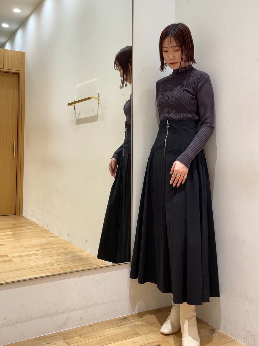 ホワイト系のブーツ、ブラック系のスカート、グレー系のニット/セーターを着用したレディースの冬コーディネートの4枚目の写真