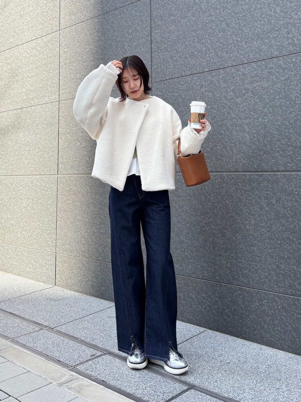 ホワイト系のブルゾン、ブルー系のデニムパンツ、イエロー系のハンドバッグを着用したレディースの冬コーディネートの2枚目の写真