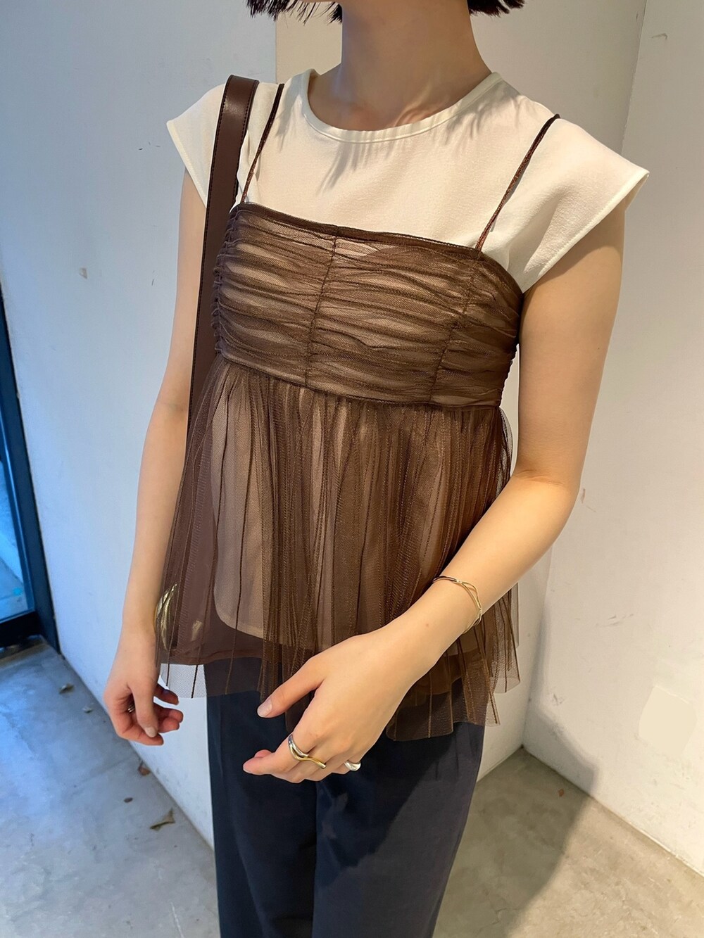 ブラウン系のTシャツ/カットソー、ブルー系のスラックス、ブラック系のサンダルを着用したレディースの春コーディネートの7枚目の写真