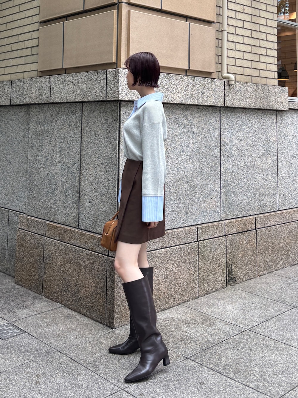 ブラウン系のスカート、グレー系のニット/セーター、イエロー系のハンドバッグを着用したレディースの秋コーディネートの2枚目の写真