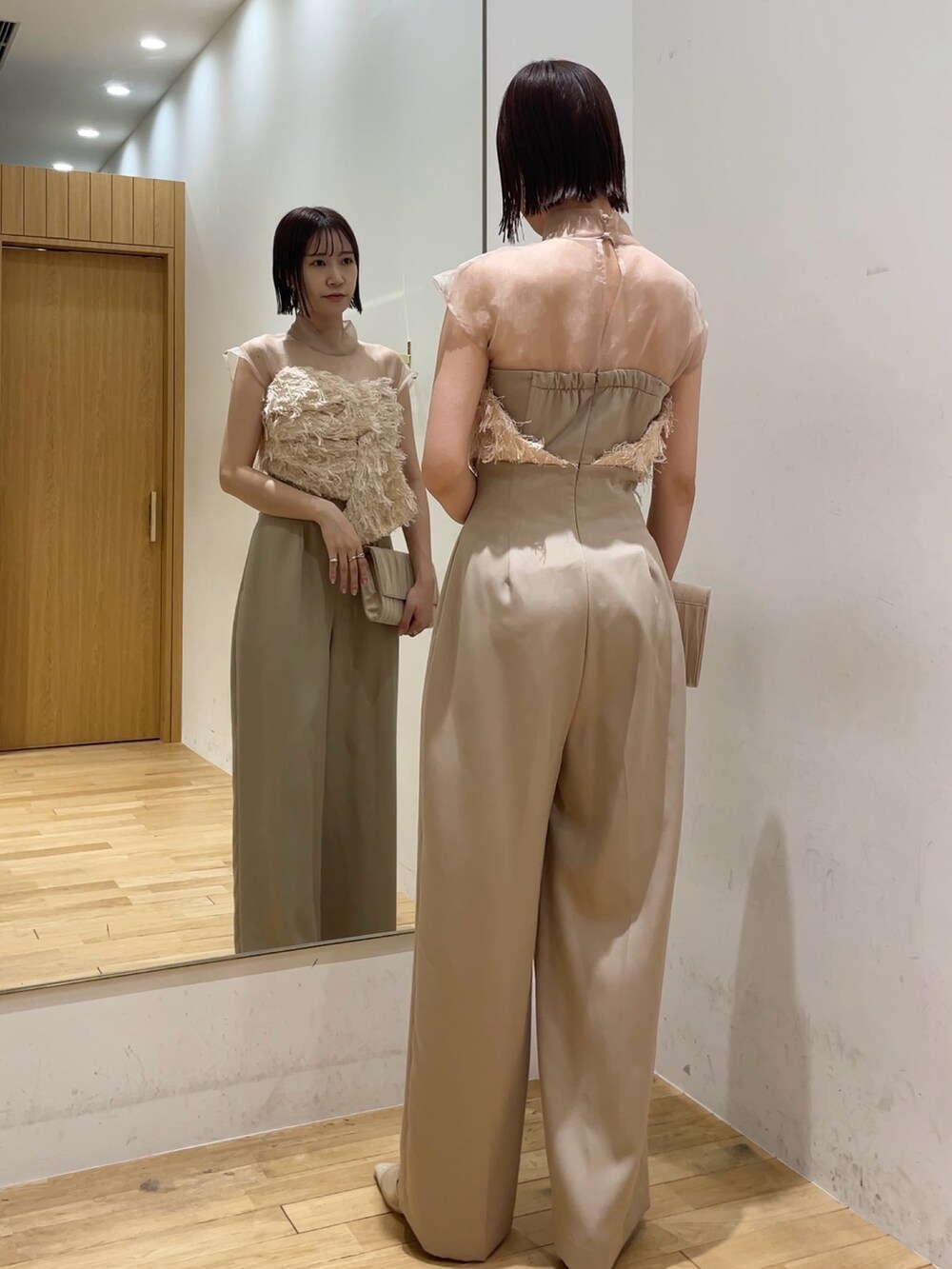 ベージュ系のパンプス、ベージュ系のパンツドレス、ベージュ系のクラッチバッグを着用したレディースの冬コーディネートの3枚目の写真