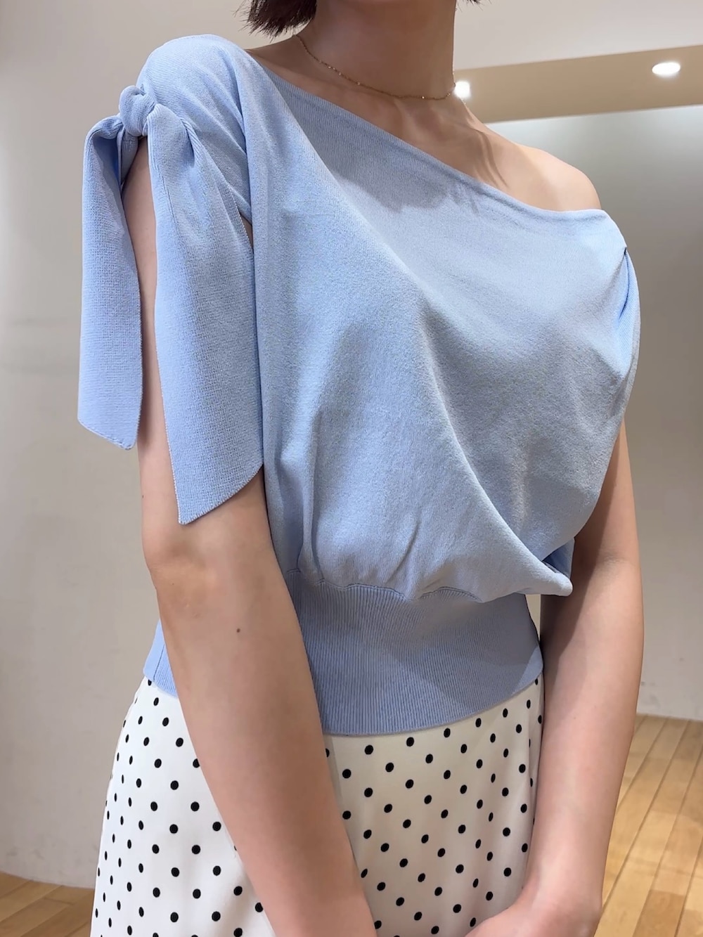 ブルー系のニット/セーター、ホワイト系のスカート、ブラック系のハンドバッグを着用したレディースの夏コーディネートの5枚目の写真