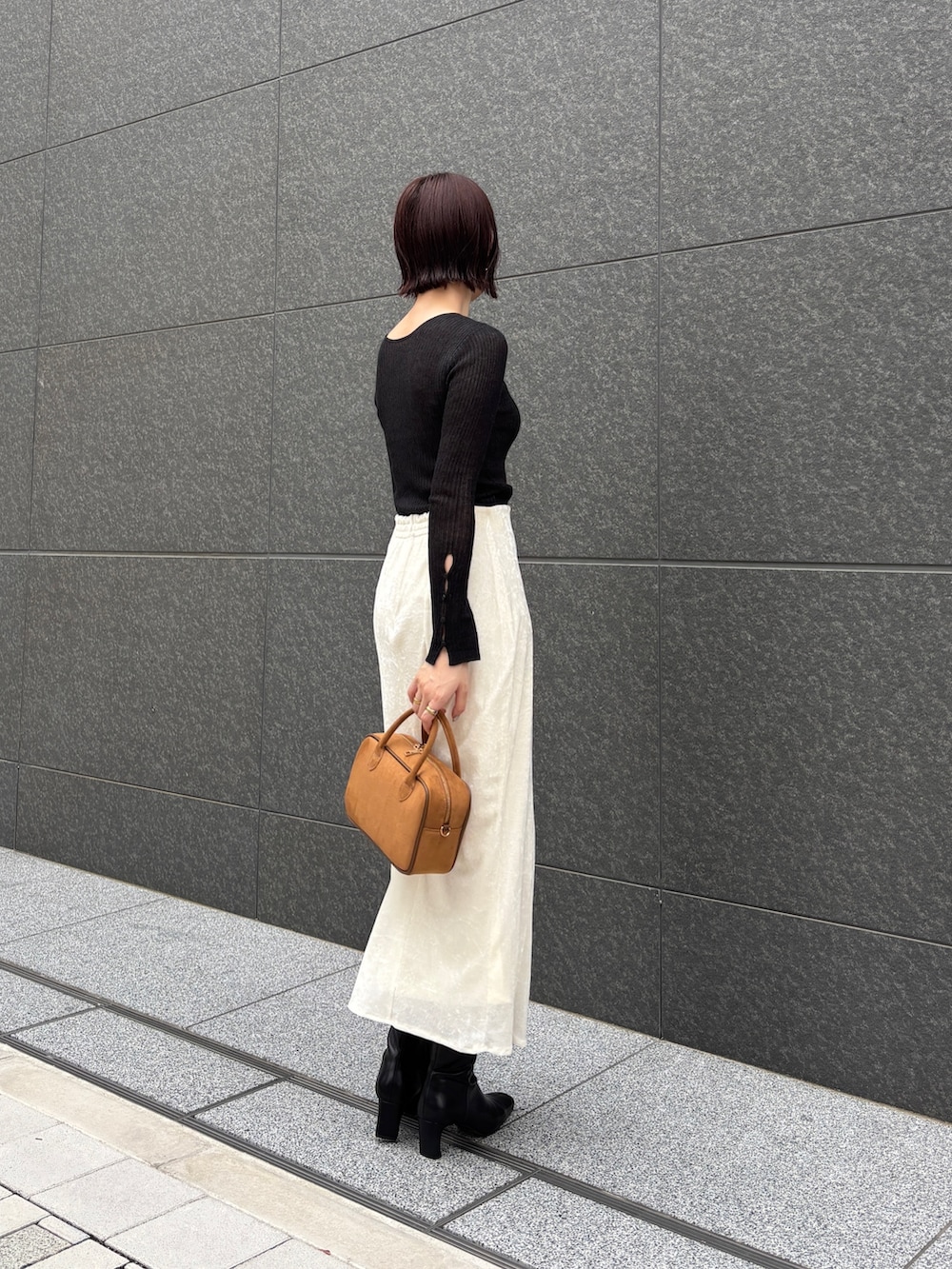 ホワイト系のスカート、ブラック系のニット/セーター、イエロー系のハンドバッグを着用したレディースの秋コーディネートの2枚目の写真