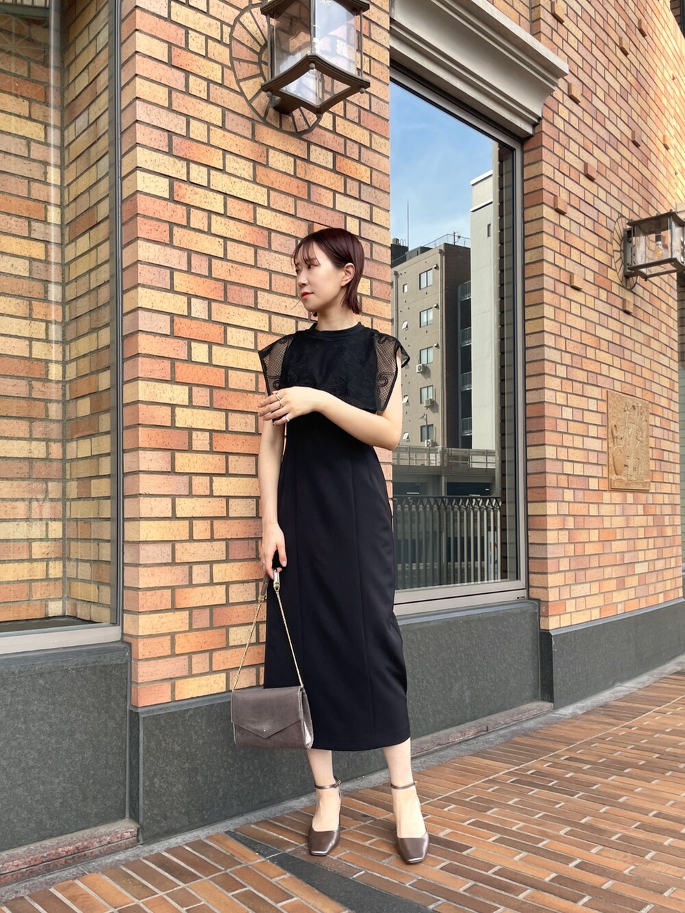 ブラック系のドレス、シルバー系のハンドバッグ、その他のパンプスを着用したレディースの秋コーディネートの2枚目の写真