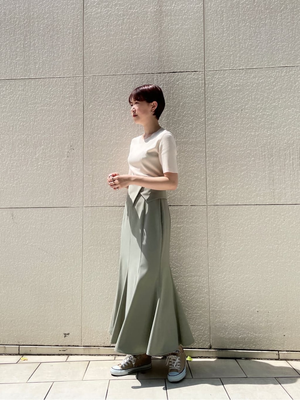 グリーン系のスカート、ホワイト系のニット/セーターを着用したレディースの春コーディネートの2枚目の写真