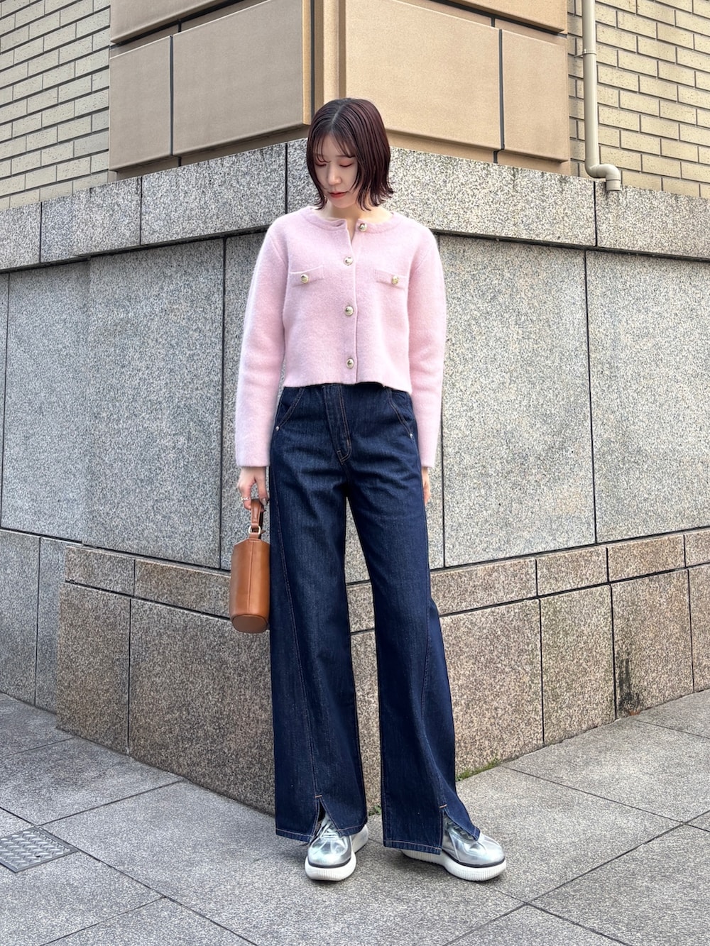 ブルー系のデニムパンツ、ピンク系のテーラードジャケット、イエロー系のハンドバッグを着用したレディースの冬コーディネートの2枚目の写真