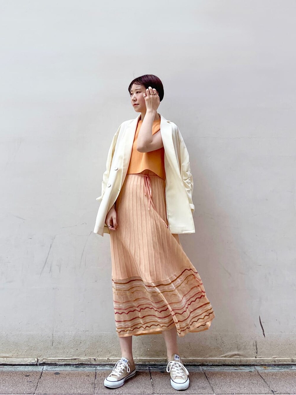 ホワイト系のテーラードジャケット、オレンジ系のワンピースを着用したレディースの春コーディネートの2枚目の写真