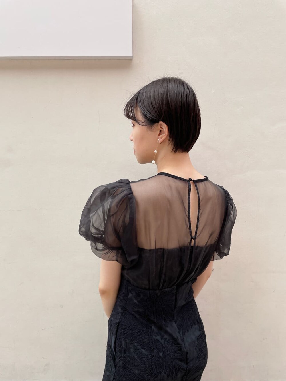 シルバー系のクラッチバッグ、シルバー系のパンプス、ブラック系のドレスを着用したレディースの夏コーディネートの6枚目の写真